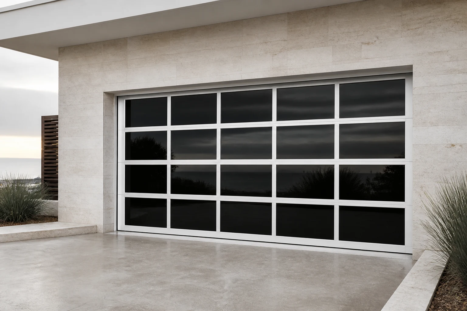 RGNL White-Frame Frameless Mirror Garage Door Courtyard Scene Illustrative application scene of a white-frame RGNL frameless mirror garage door with dark reflective glass panels in a coastal courtyard